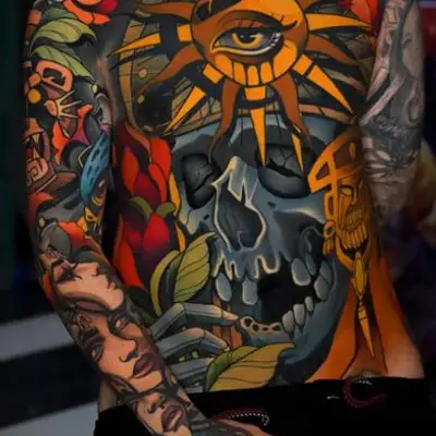 Colorful chest tattoo with a sun, eye, skull, and roses.