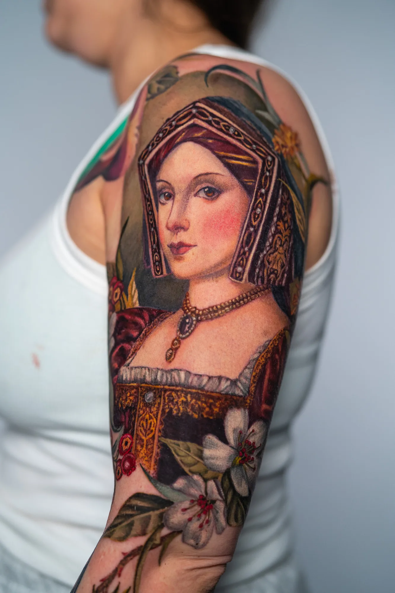 Portrait tattoo of a woman in Renaissance attire on upper arm.