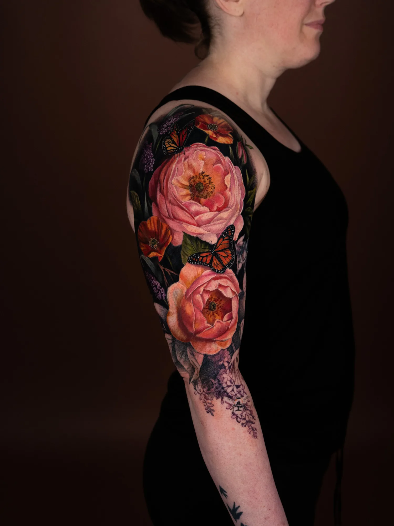 Colorful floral and butterfly tattoo on upper arm.