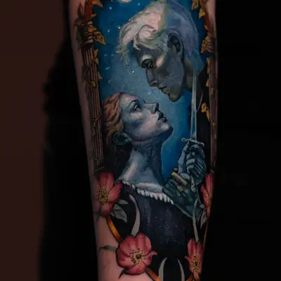 Tattoo of two figures in profile under a crescent moon with floral details.