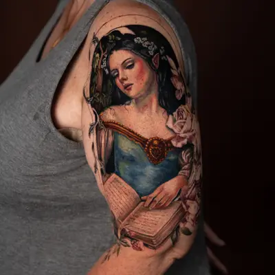 Tattoo of an elf reading a book with floral elements on the upper arm.