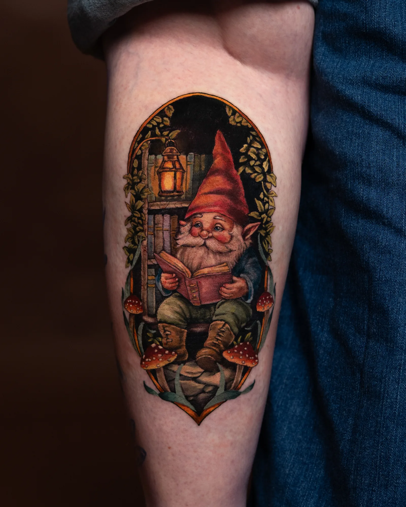 Tattoo of a gnome reading in a woodland setting.