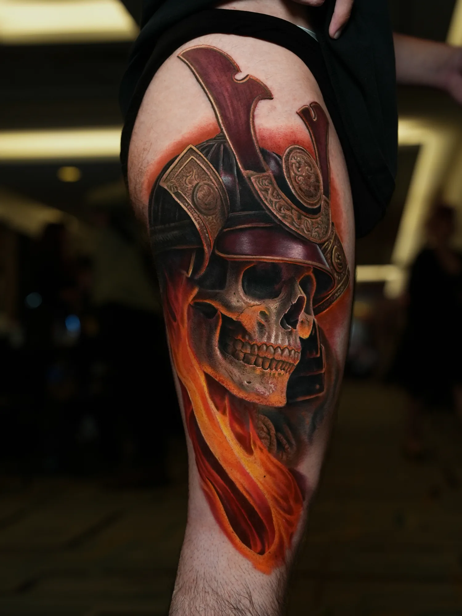 A striking skull with a samurai helmet and flames tattooed on the thigh.