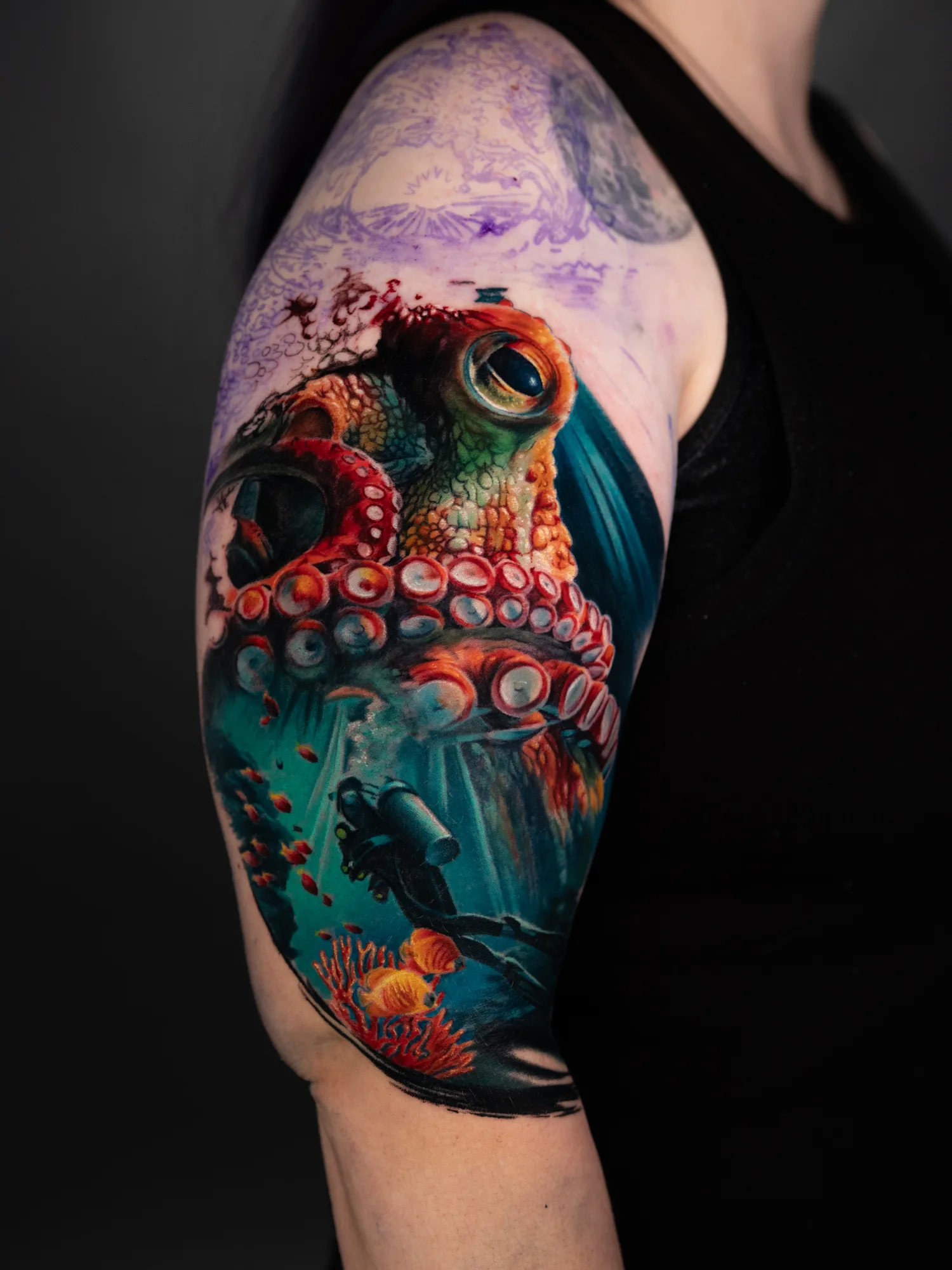 Colorful octopus tattoo with diver, coral, and fish on arm.