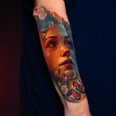 Colorful portrait tattoo with clownfish on forearm.