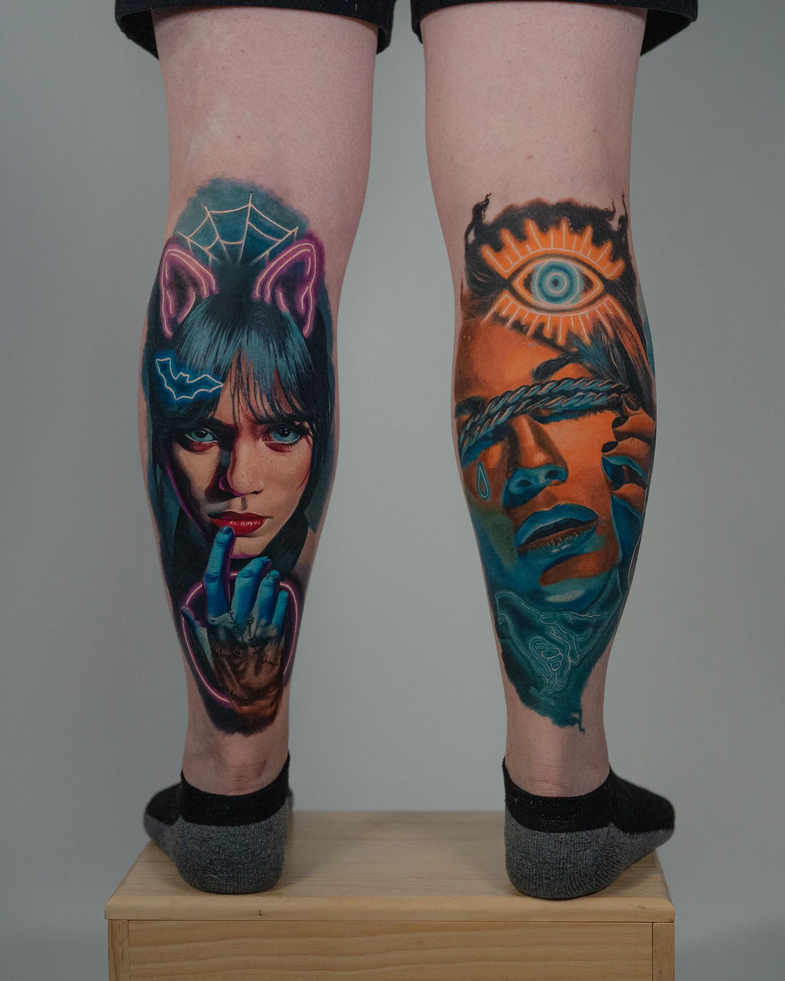 Two calf tattoos of surrealistic portraits with vivid colors.