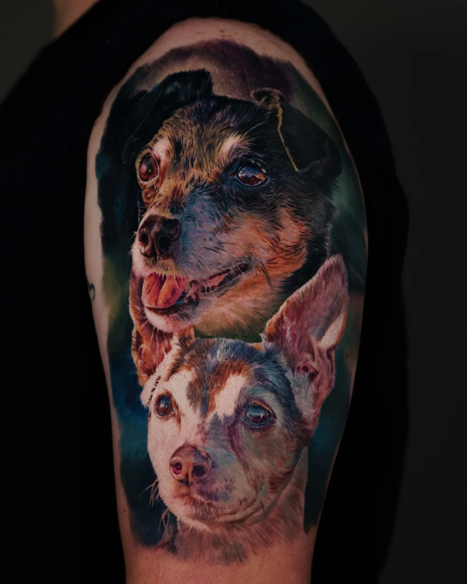 Realistic tattoo of two dogs on upper arm.