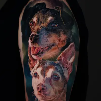 Realistic tattoo of two dogs on upper arm.
