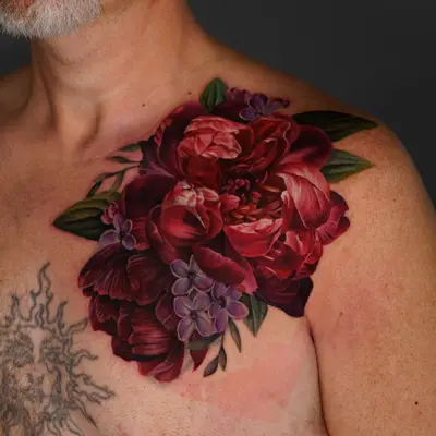 A vibrant floral tattoo covering the shoulder and upper chest area, featuring red peonies and purple flowers.