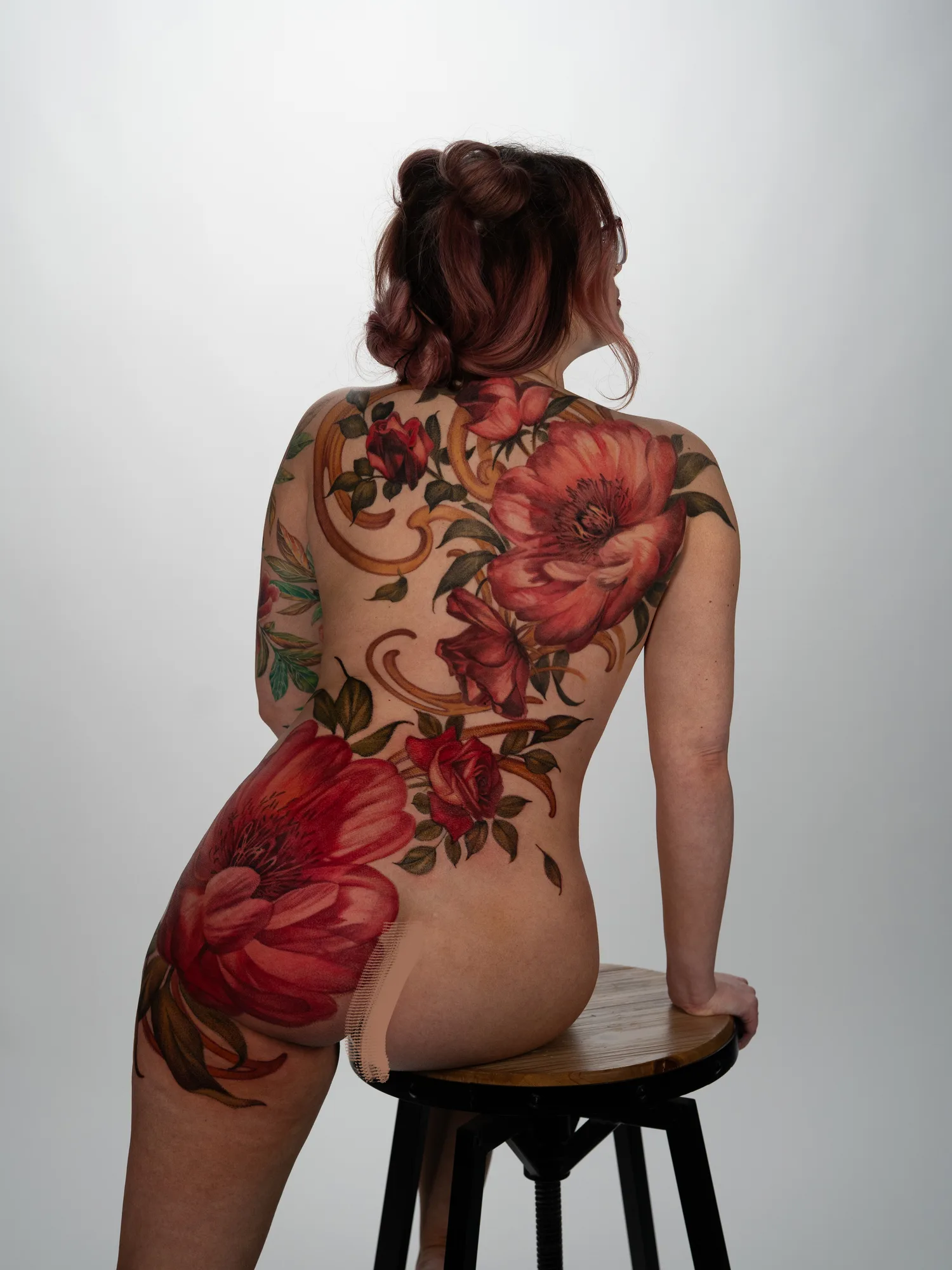Vibrant floral tattoo covering the back and thigh, featuring peonies and roses.