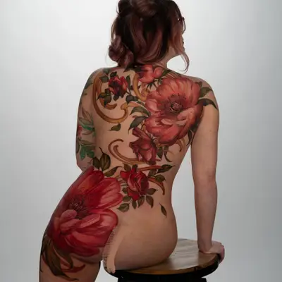 Vibrant floral tattoo covering the back and thigh, featuring peonies and roses.