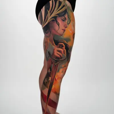 A leg tattoo featuring a woman with a sword and an American flag, showcasing vivid colors.