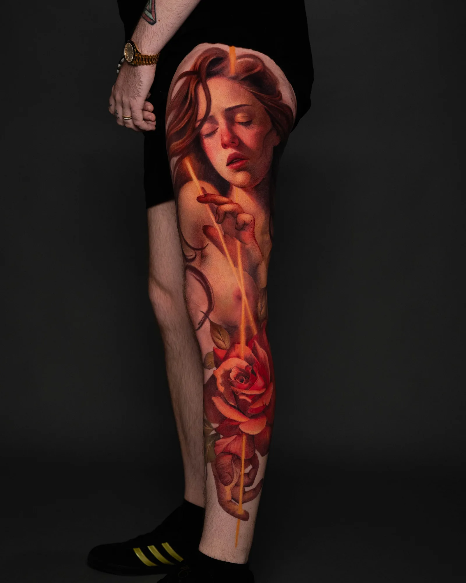 A vibrant tattoo of a woman and roses on a thigh, showcasing rich colors and painterly style.