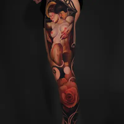 Tattoo on thigh featuring two nude figures with flowers and ornate elements.