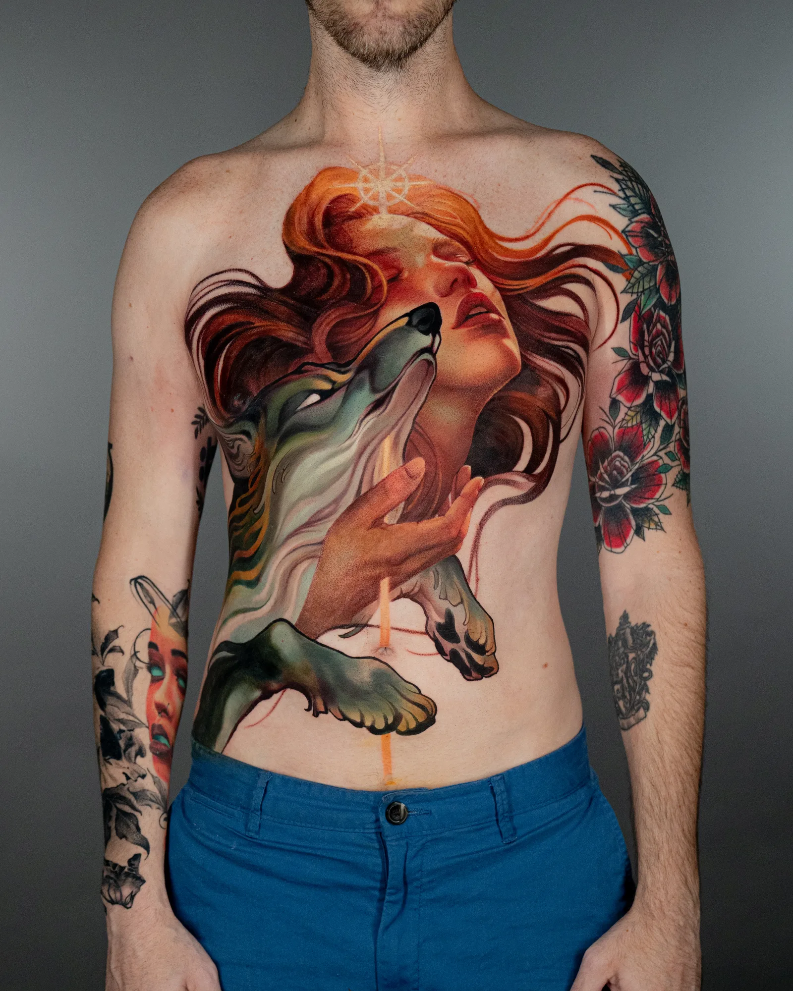 A colorful tattoo featuring a woman with flowing hair and a wolf's head on a man's torso.