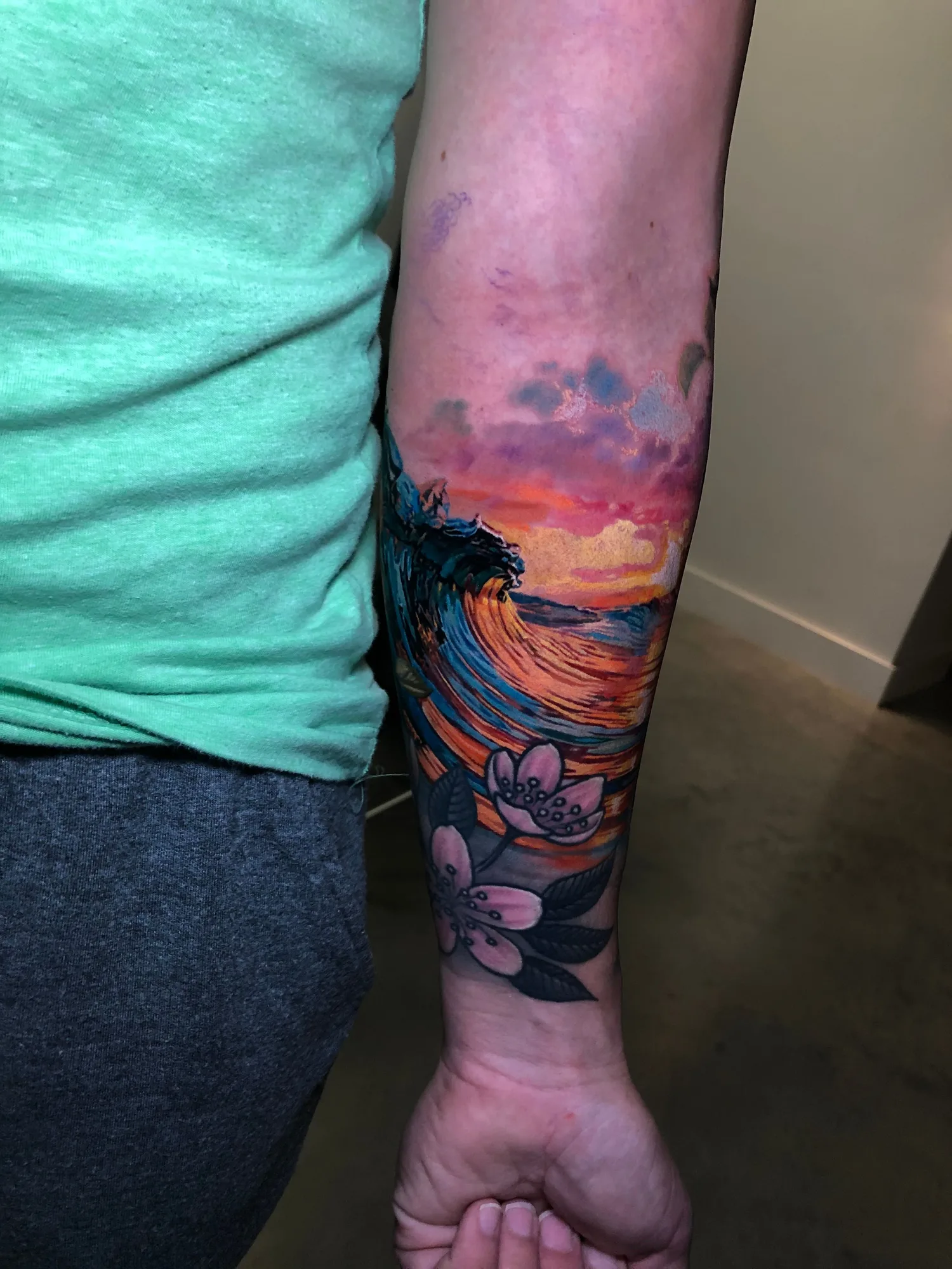 Vibrant tattoo featuring waves and flowers on a forearm.