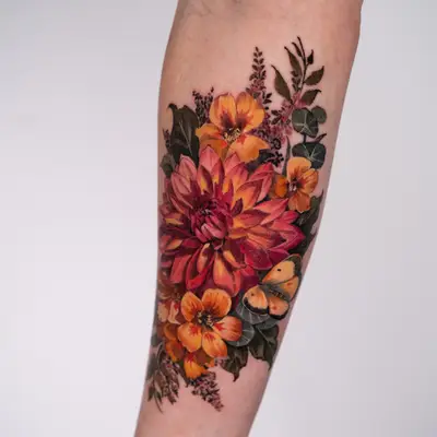 Full color realism tattoo of a red and orange dahlia with orange blooms, heather sprigs, eucalyptus and a yellow butterfly, on an inner forearm.