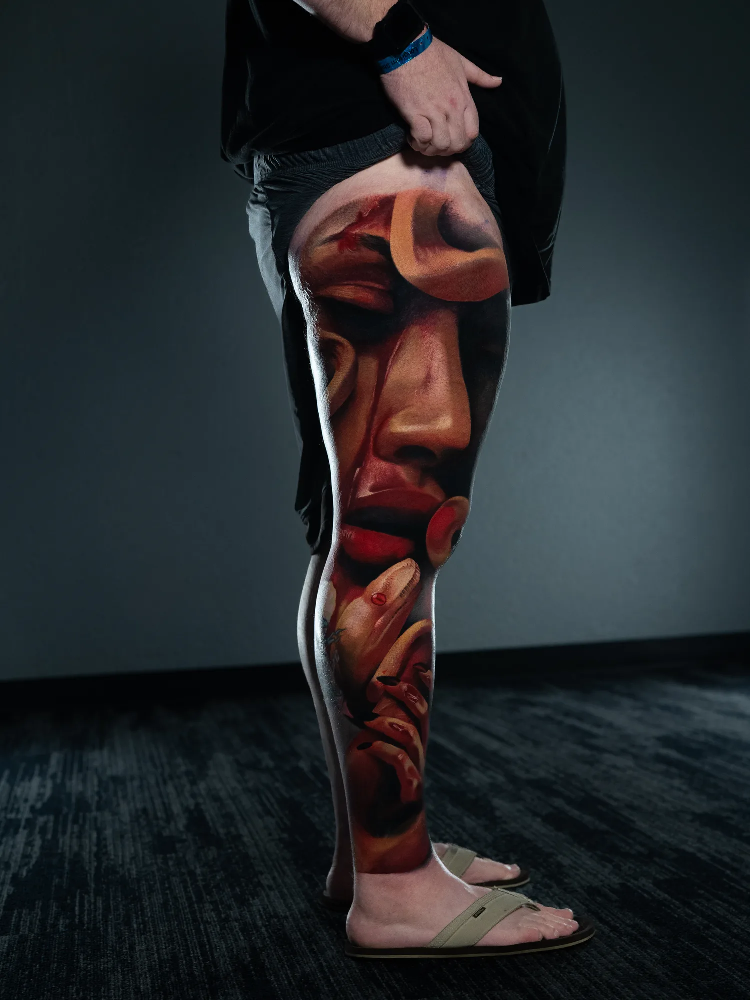 Realistic leg tattoo with abstract face and hands