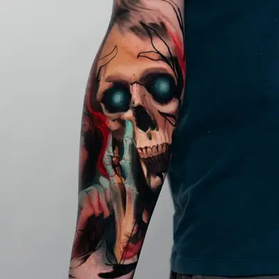Tattoo of a skull with blue eyes and abstract elements on an arm.