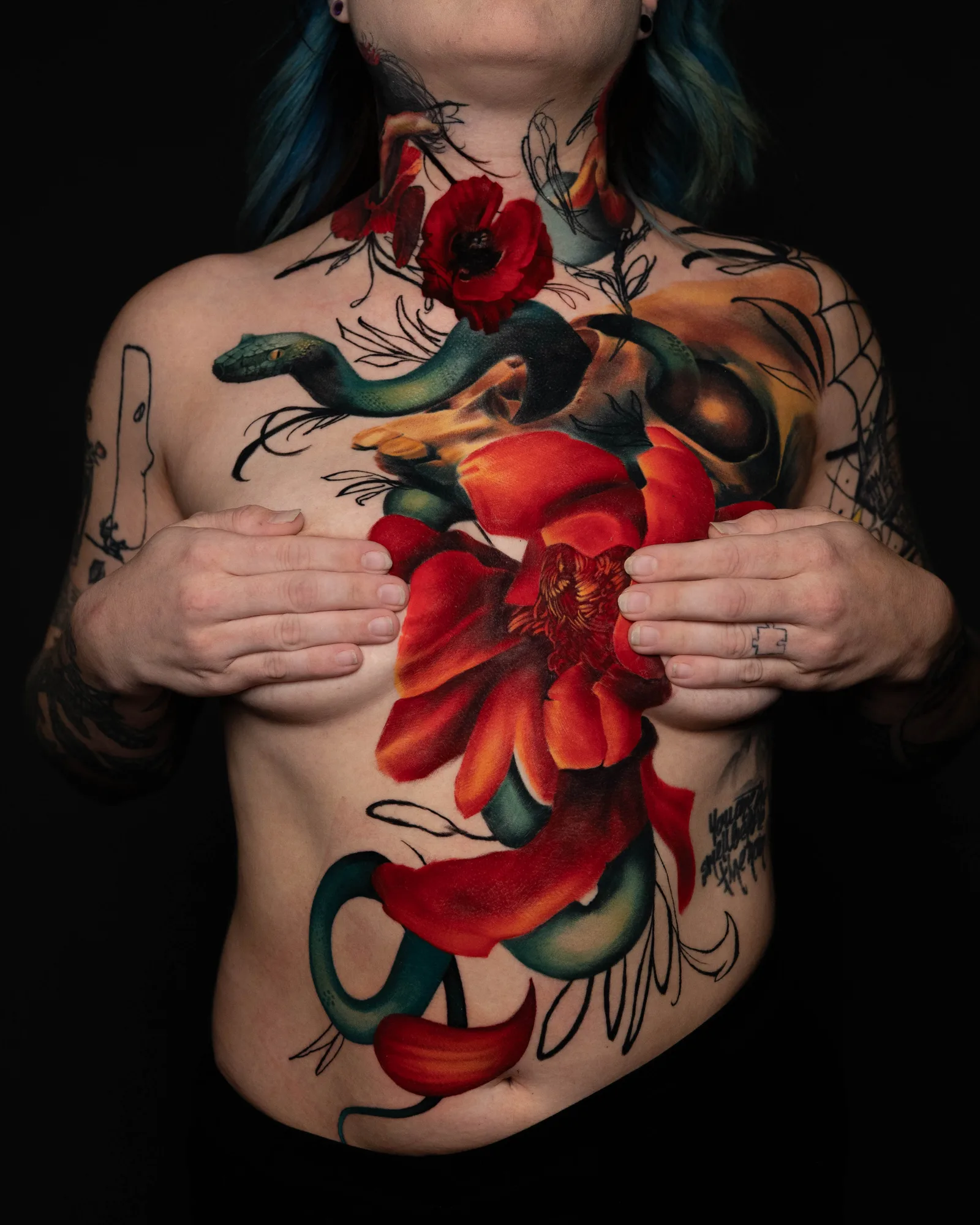 Tattoo of a green snake entwined with red flowers on chest and neck.