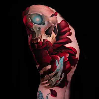 Tattoo of a skull with glowing eyes and red roses on an arm.