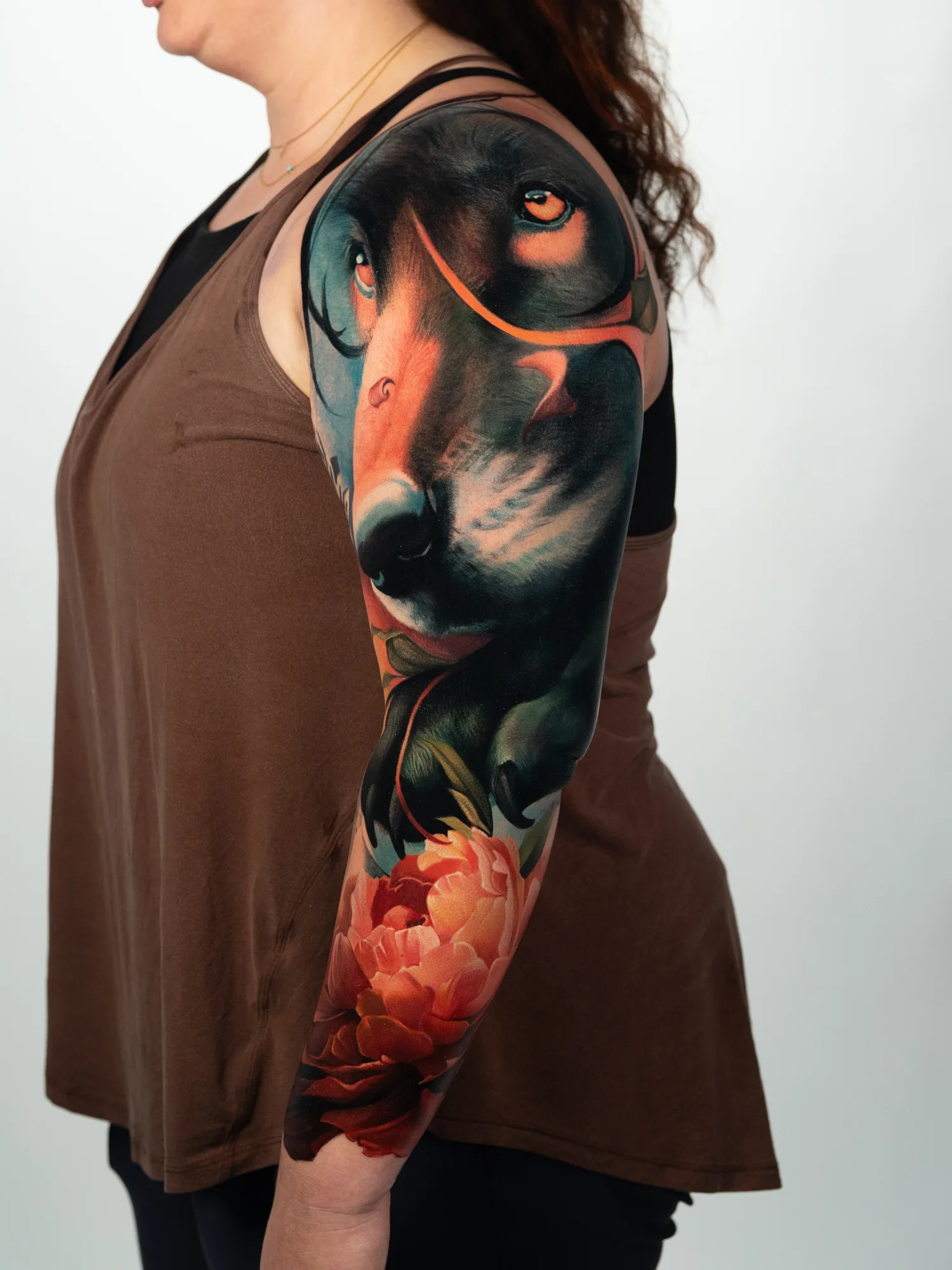 Colorful full-sleeve tattoo of a wolf and flowers on an arm.