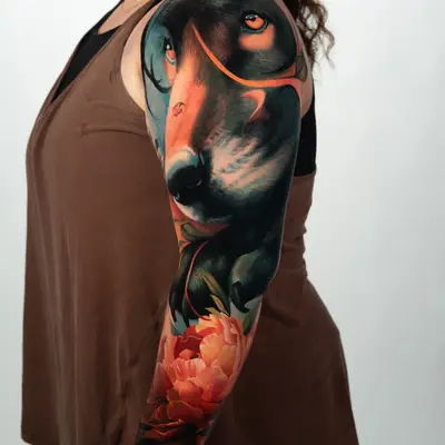 Colorful half-sleeve tattoo of a wolf and flowers on an arm.