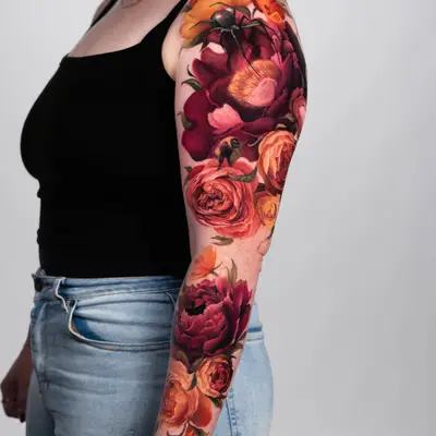 Floral sleeve tattoo with vibrant roses and a spider