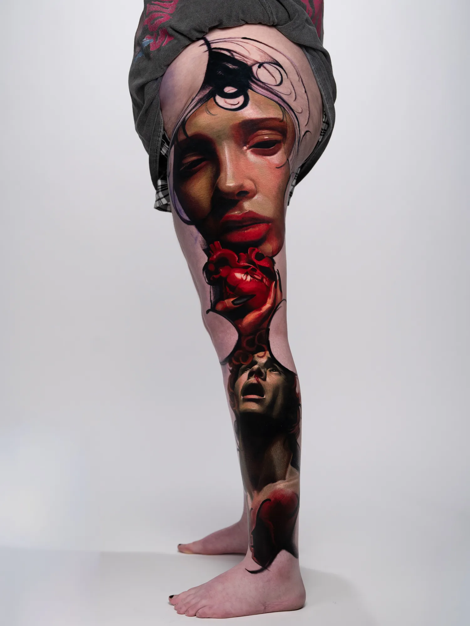 Surrealistic leg tattoo with faces and abstract elements