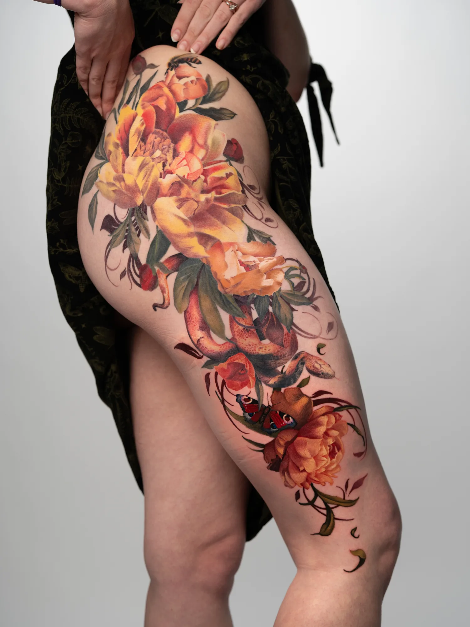 Colorful floral tattoo on thigh with snake and butterfly