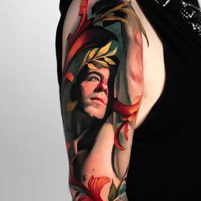 Colorful arm tattoo of a man's face surrounded by floral elements.