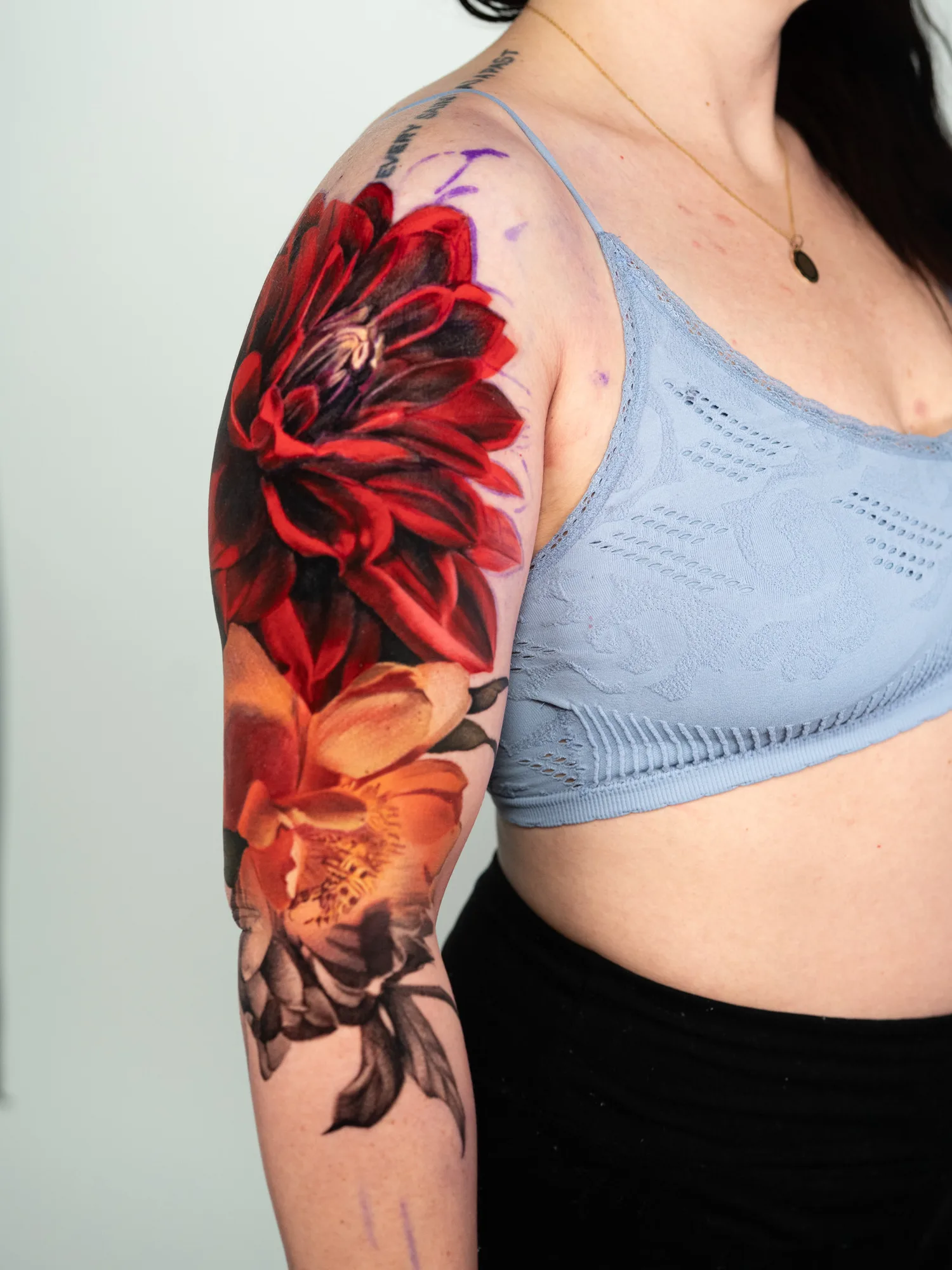 Half sleeve tattoo of a peony and dahlia in color.