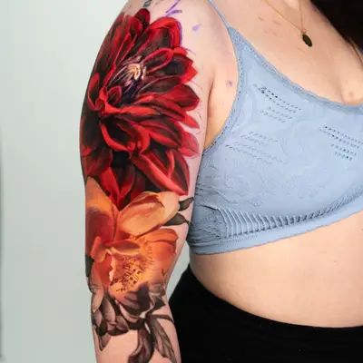 Half sleeve tattoo of a peony and dahlia in color.