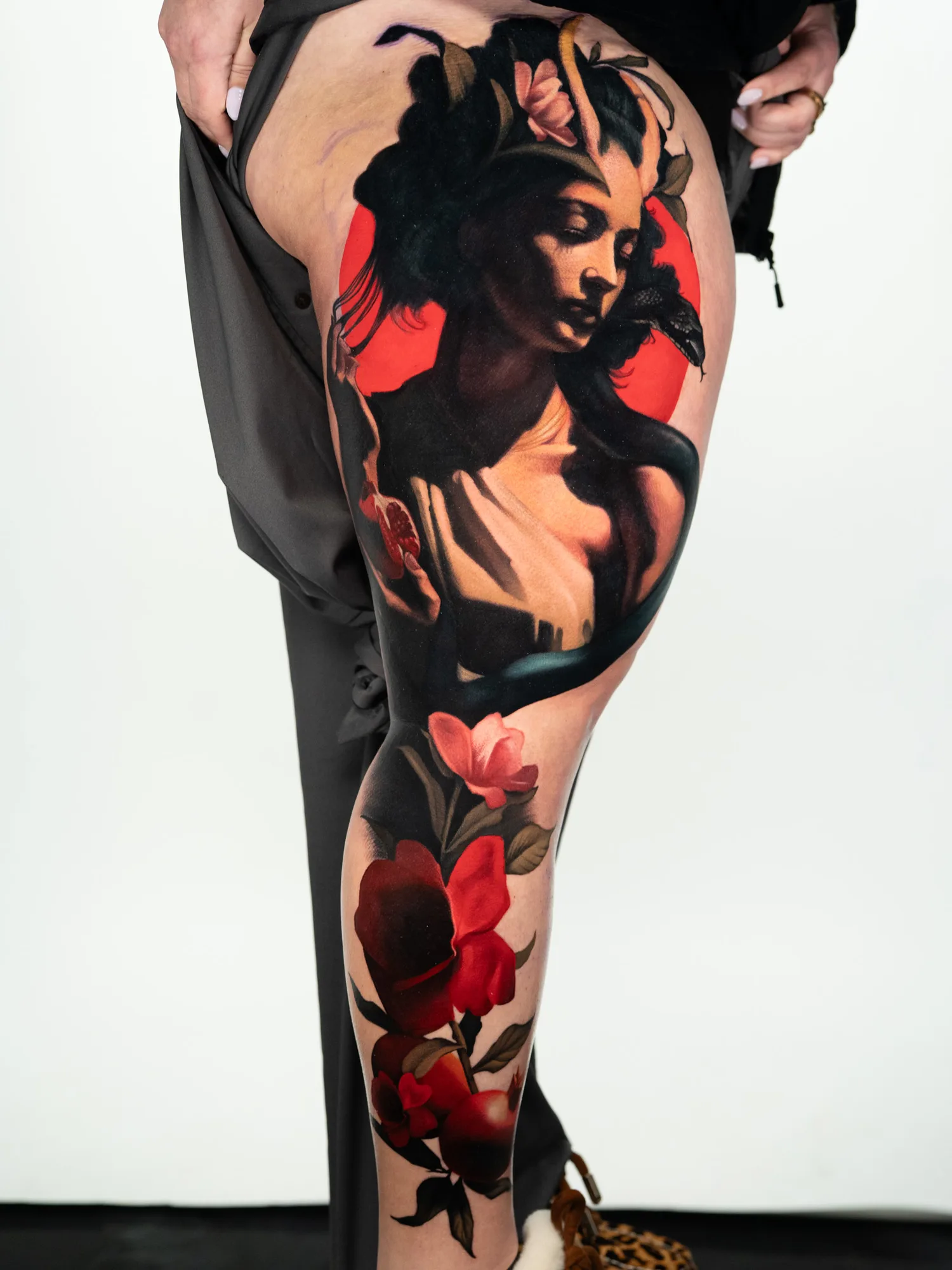 A striking leg tattoo featuring a woman in a portrait style surrounded by vibrant flowers.
