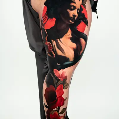 A striking leg tattoo featuring a woman in a portrait style surrounded by vibrant flowers.