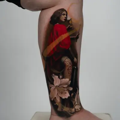 Tattoo of a woman in a red robe, with a white lily on a woman's calf.