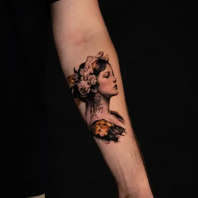 A woman with a floral crown, portrayed in a realistic tattoo on forearm.