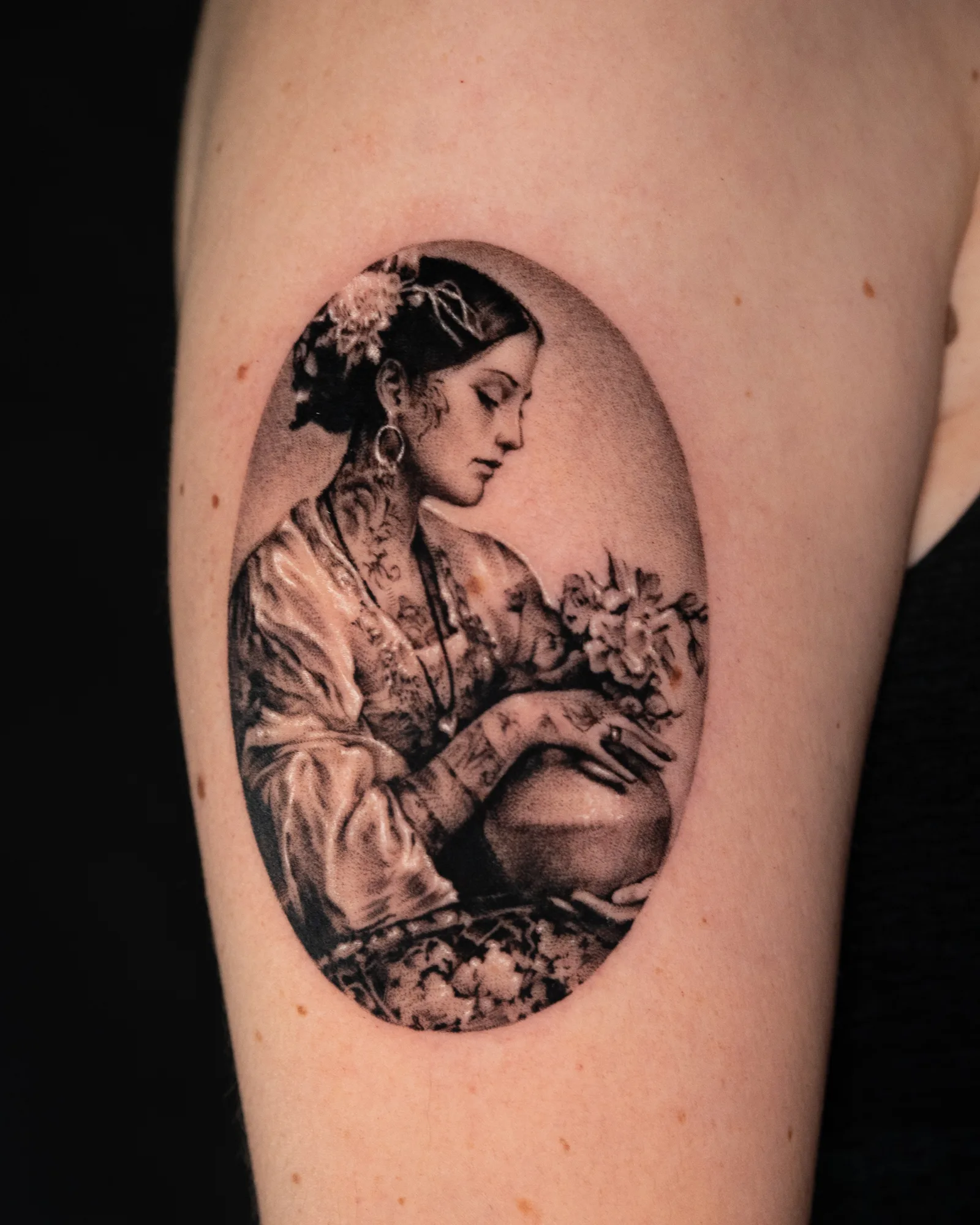 Micorealism tattoo of a woman with tattoos and flowers in her hair.
