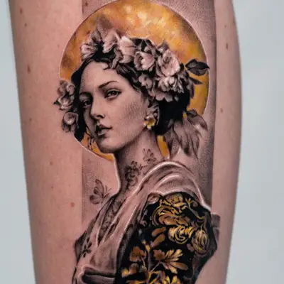 Tattoo of a female portrait in black and grey set on a gold leaf circle.