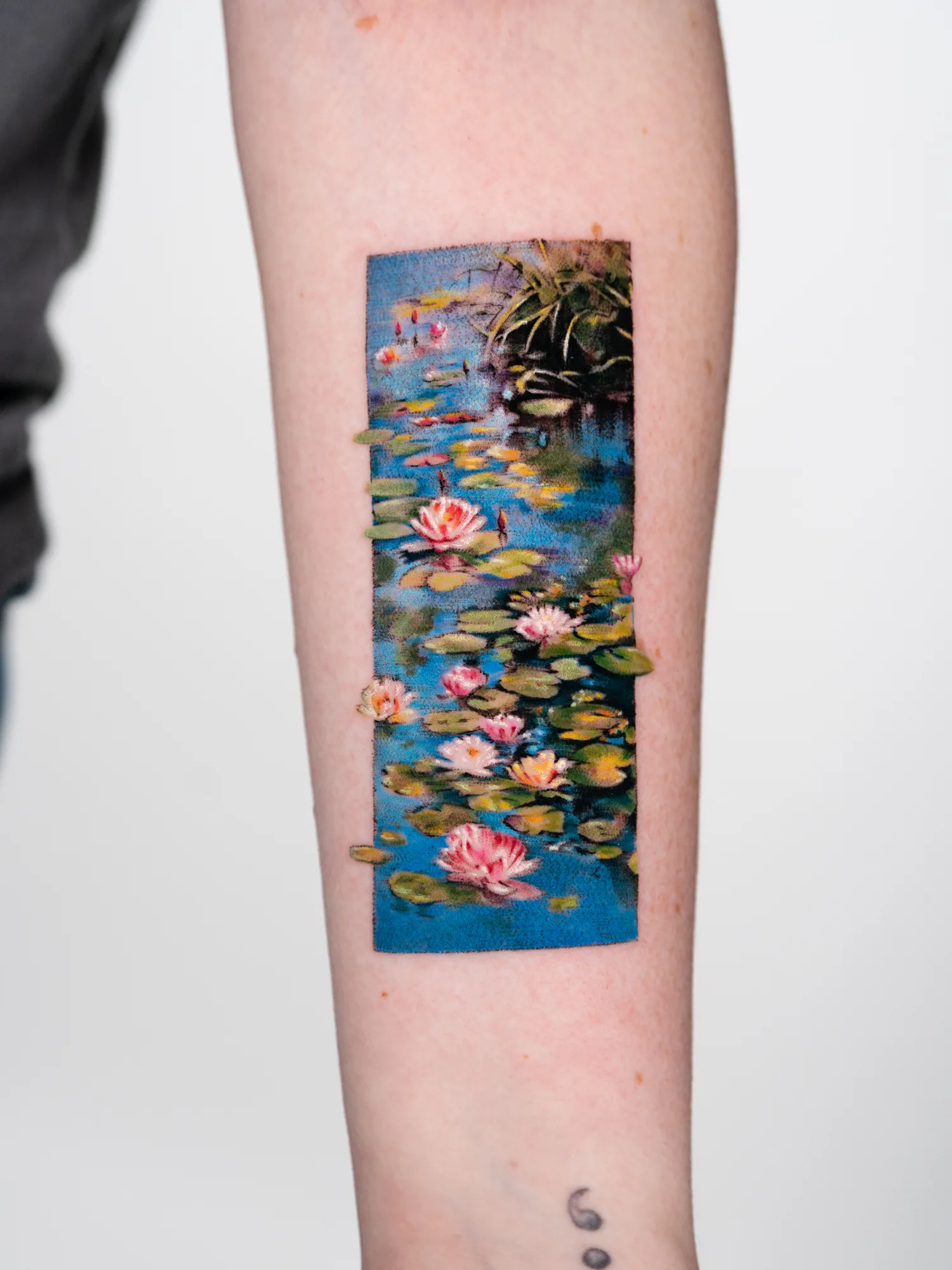 Tattoo of Monet's Water Lilies painting on an inner forearm.