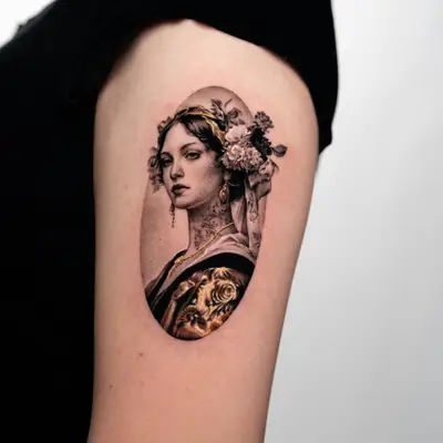Black and grey tattoo of a woman with flowers in her hair and gold accents.