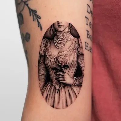Tattoo of a Victorian lady in an oval holding a rose.