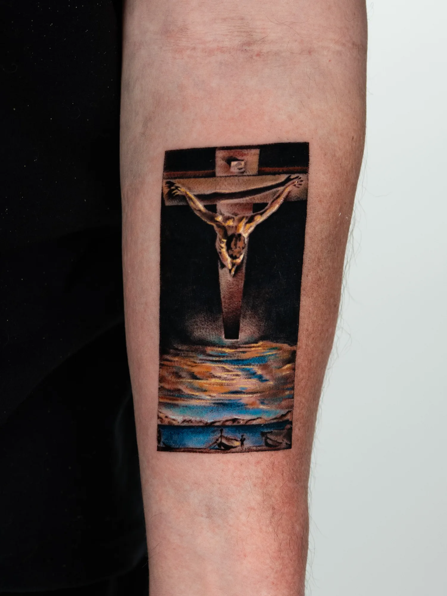 Painting tattoo of Salvador Dali's Christ of Saint John of the Cross on the forearm.