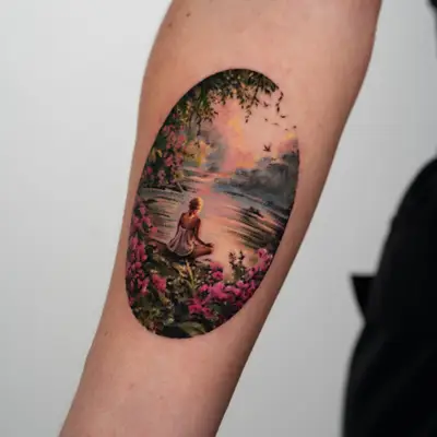 Landscape tattoo of a women sitting in a garden on a riverbank gazing at a sunset.
