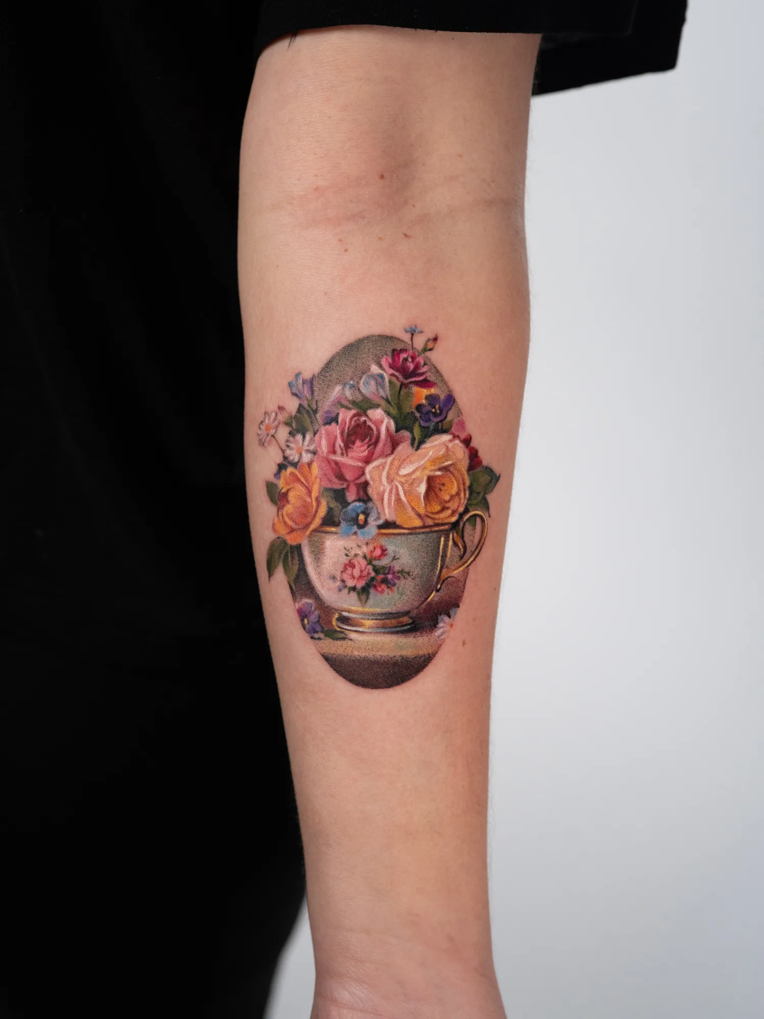 Tattoo of a still life painting with roses in a teacup.