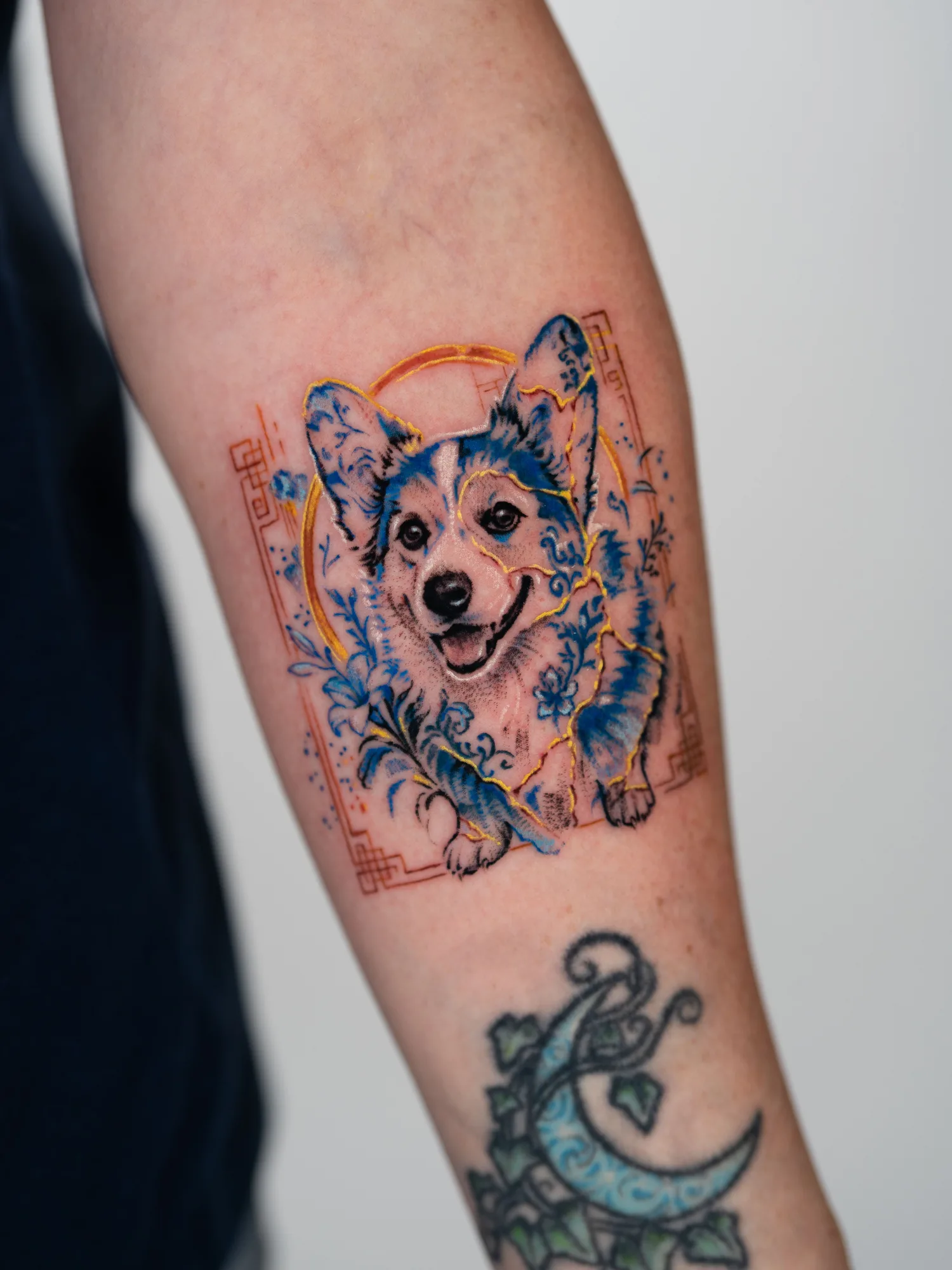 Realistic portrait tattoo of a Corgi with gold Kintsugi and porcelain elements done on a forearm in a microrealism style.
