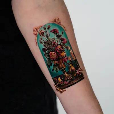 Color microrealism tattoo of a decaying floral still life in an arched frame, with a brass urn, a burning candle and a moth, on a forearm.