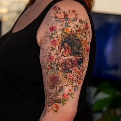 Floral sleeve tattoo with a woman in ornate frame on upper arm.