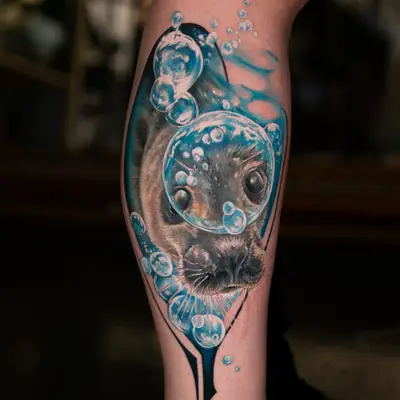 Realistic tattoo of a seal with bubbles underwater on a leg.