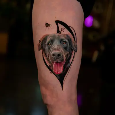 Realistic dog portrait tattoo on thigh with abstract elements.